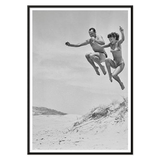 Two Tivoli Stars performing an acrobatic jump on a sandy beach in swimsuits Acrobatics at the Beach poster, with black aluminium frame on white background