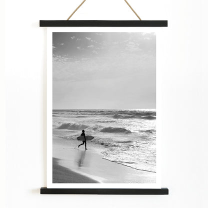 Black and white poster of a surfer with a board entering the ocean titled Surfer in Portugal by artist Black, with wooden magnetic frame on white background