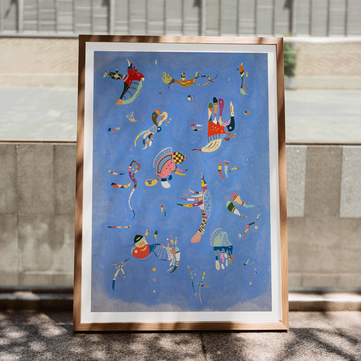 Bleu de Ciel by Wassily Kandinsky abstract blue artwork poster with colorful geometric shapes and vibrant colors on a blue background, framed and displayed in modern living room decor