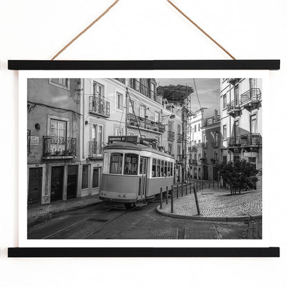 Lisbon Tramway 28 Black and White historic tram navigating cobblestone streets in Lisbon street scene poster, with wooden magnetic frame on white background