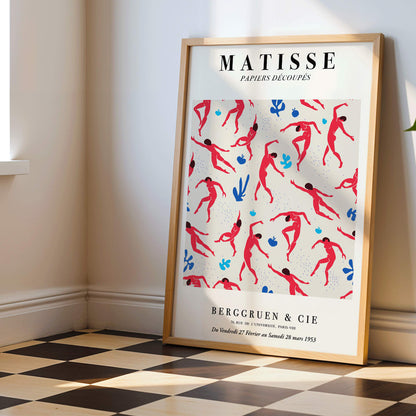 Henri Matisse Dancing Figures Exhibition Poster with vibrant red and blue design featuring red cut out figures on a patterned background with exhibition details, framed and displayed in home decor