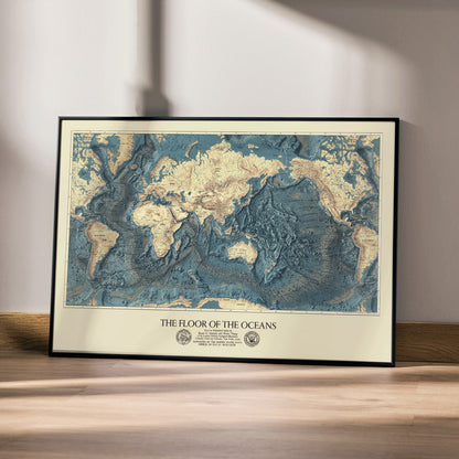 World map artwork showing ocean floors titled The Floor of the Oceans bathymetric map poster, framed and displayed in home decor