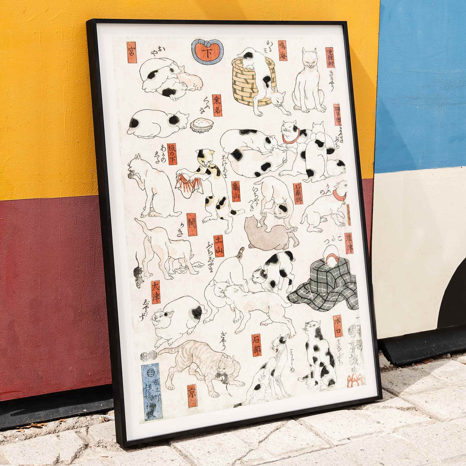 Playful and resting cats in traditional Japanese ukiyo-e art by Utagawa Kuniyoshi featuring multiple cats in various poses with Japanese elements, framed and displayed in home decor