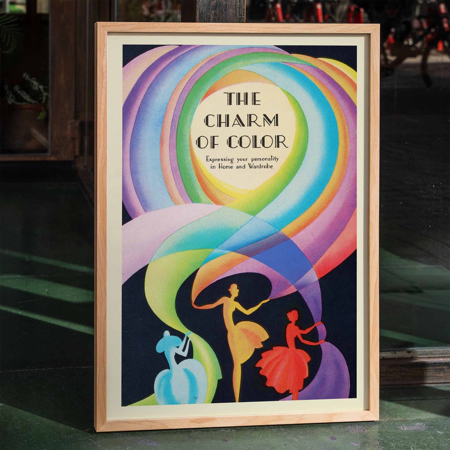 Colorful poster of The Charm of Color by Marie Josephine Carr featuring elegant dancers and swirling rainbow patterns, framed and displayed in home decor