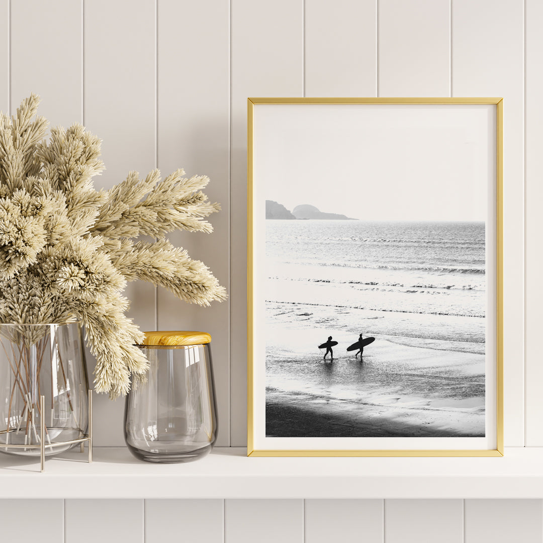 Black and white poster of surfers walking along the beach Surfers walking on the beach artwork, framed and displayed in home decor