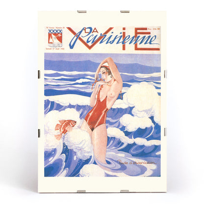 Art Deco poster of La Vie Parisienne by Umberto Brunelleschi showing a woman in a red swimsuit standing in ocean waves with a fish, framed and displayed in modern living room decor